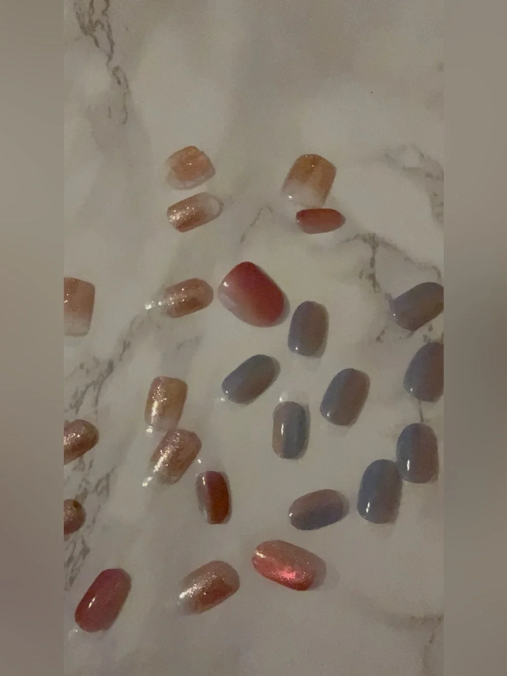 Assorted Press-On Nail Set in Rose Gold, Coral, and Blue with black pouch.